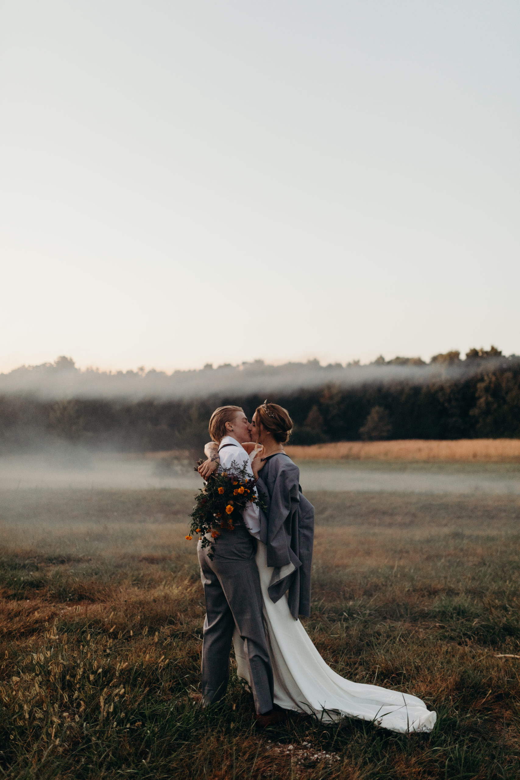 LGBT couple running through field in outdoor elopement ceremony