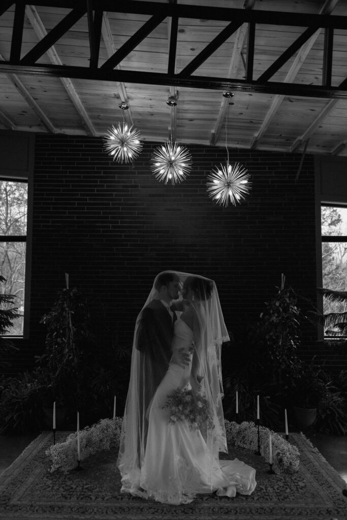 Dramatic wedding veil wrapped around a couple ready to kiss 